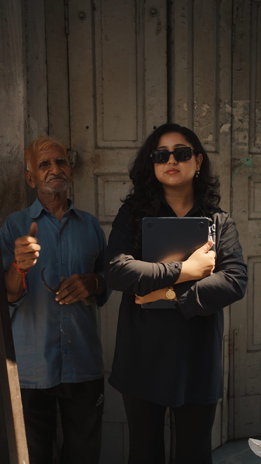 A crew member holding a laptop beside an elderly man in a doorway