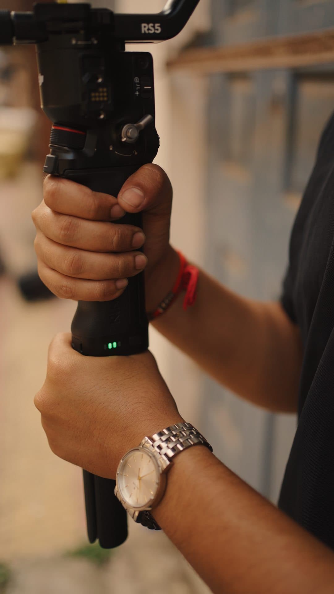 Close-up of hands gripping a gimbal handle, a wristwatch catching the light