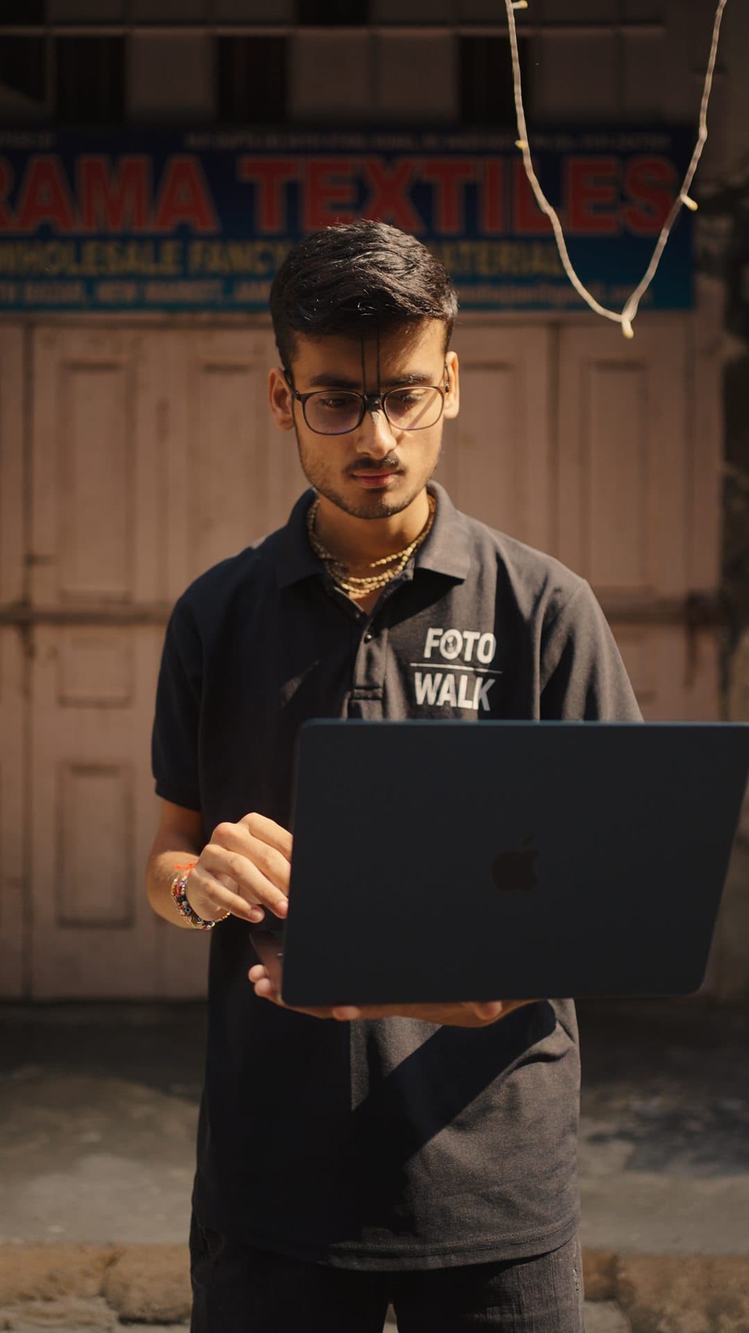 Crew member holding an open laptop beneath the Rama Textiles sign