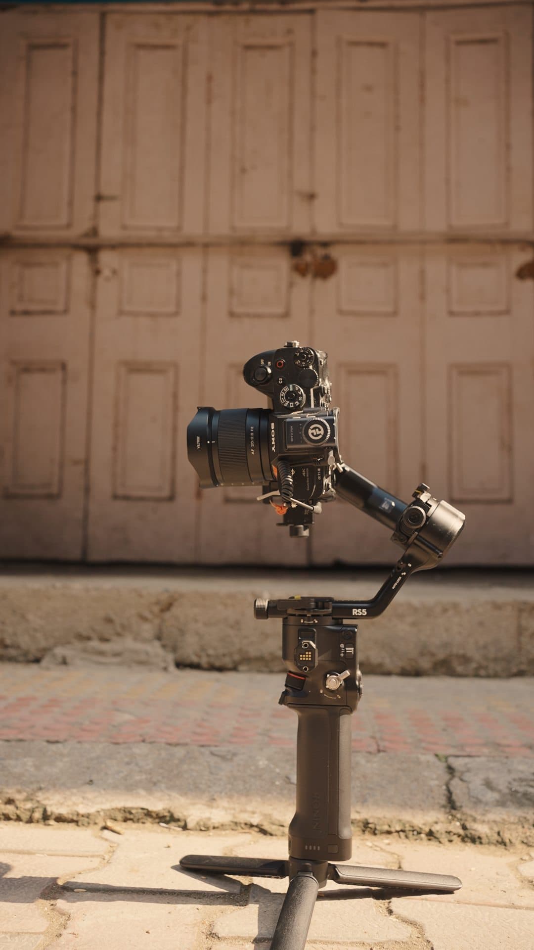A gimbal-mounted camera standing on its own in front of old wooden doors